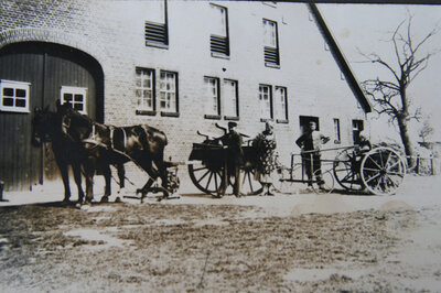 Working horses and family in front of the farm building